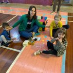 Mãe e filho sentados no chão do ginásio durante a homenagem do Dia das Mães