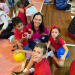 Mãe e filho sentados no chão do ginásio durante a homenagem do Dia das Mães