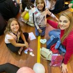 Mãe e filho sentados no chão do ginásio durante a homenagem do Dia das Mães
