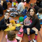 Mãe e filho sentados no chão do ginásio durante a homenagem do Dia das Mães