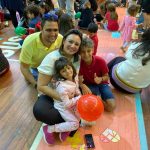 Mãe e filho sentados no chão do ginásio durante a homenagem do Dia das Mães