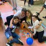 Mãe e filho sentados no chão do ginásio durante a homenagem do Dia das Mães