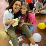 Mãe e filho sentados no chão do ginásio durante a homenagem do Dia das Mães