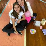 Mãe e filho sentados no chão do ginásio durante a homenagem do Dia das Mães