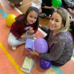 Mãe e filho sentados no chão do ginásio durante a homenagem do Dia das Mães