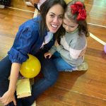 Mãe e filho sentados no chão do ginásio durante a homenagem do Dia das Mães