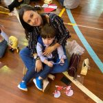 Mãe e filho sentados no chão do ginásio durante a homenagem do Dia das Mães