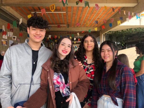 Quatro estudantes posando juntos sob as bandeirinhas do Arraiá do Coração