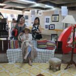 Cenário montado com poltrona vermelha e quadros na Mostra Cultural