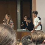 Aluno fala ao microfone no púlpito do auditório durante o Show de Talentos