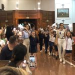 Alunos vestidos de branco em procissão pelo corredor do santuário na coroação de Nossa Senhora