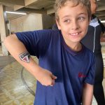 Criança mostra a pintura feita no braço durante o Férias no Coração
