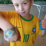 Criança mostra a pintura feita no braço durante o Férias no Coração