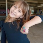 Criança mostra a pintura feita no braço durante o Férias no Coração