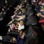 Crianças assistem ao filme na sessão de cinema do Férias no Coração