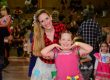 Mãe e filha com trajes juninos dançando no ginásio durante a festa junina