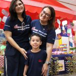 Educadoras e aluna posam no estande da Mostra Cultural