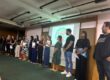 Equipe do colégio perfilada no auditório durante a primeira reunião de pais de 2026, com a projeção ao fundo